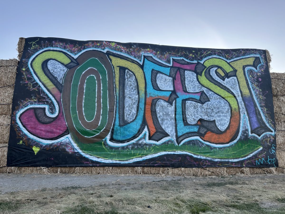 A large hand-painted SODFEST banner in graffiti lettering hung on a wall of hay bales, photographed in daylight against open Idaho sky.